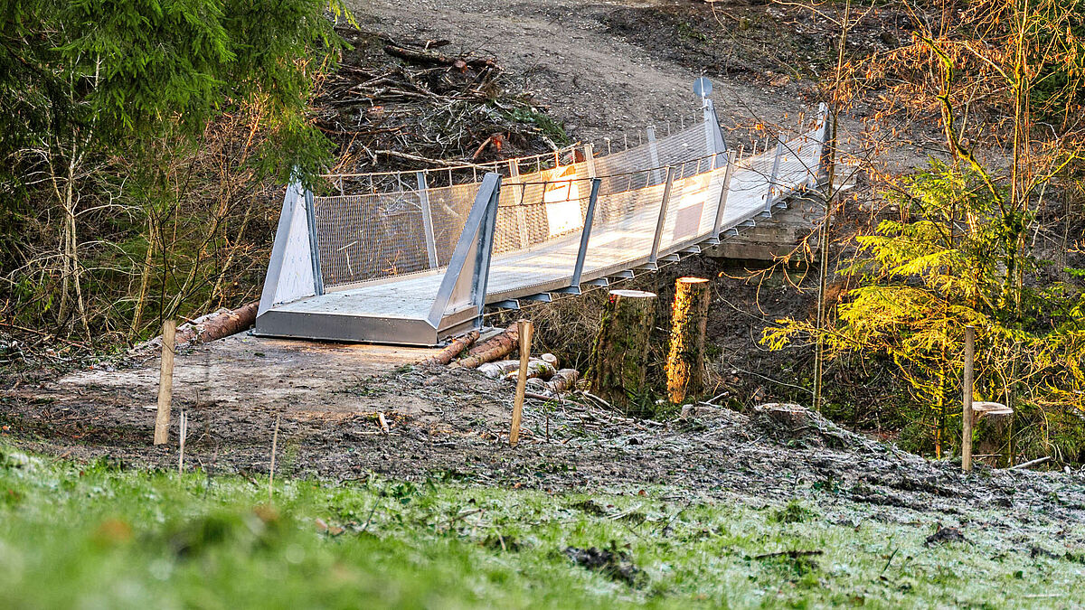 La passerelle, suspendue à des câbles métalliques de 23 m de long, est maintenue par deux chevalets de tension en acier ; sécurité anti-chute avec filets en acier inox type Webnet.